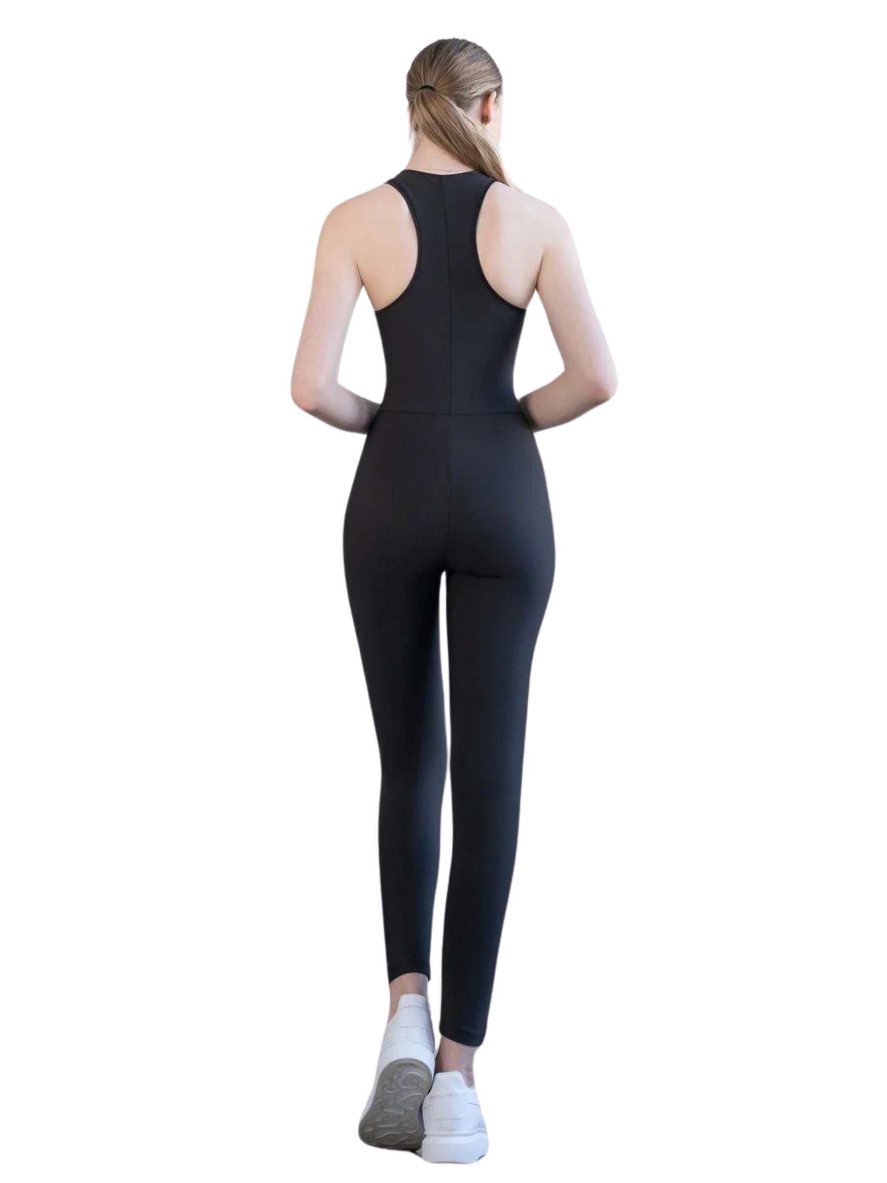 Eine Person in Lisminas 2852 Zipper Jumpsuit in Schwarz mit weißen Turnschuhen, die vor einem weißen Hintergrund mit dem Gesicht nach außen blickt.